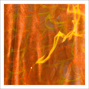 Rainbow Squared Series Six 10. Orange Yellow. A stick of incense burns yellow smoke that looks like a flame in front of a backdrop of a staticky orange velvet curtain and an orange yellow drawings made by the artist and her daughter